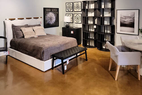 Dovetail Market Samples Bedroom set up with a upholsterd white fram and dark brown comforter, black bench, and black bookshelf and nightstand